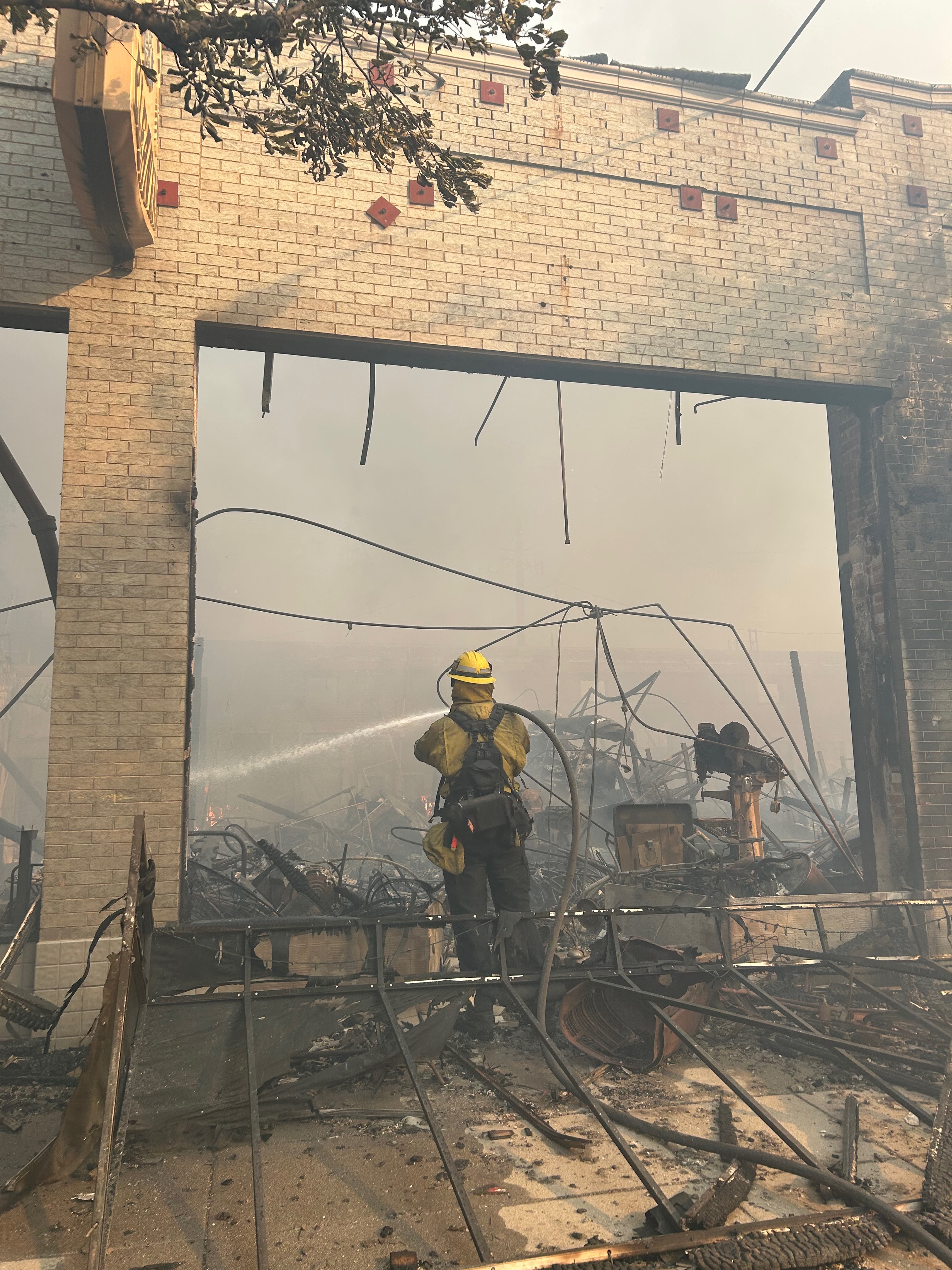 A firefighter hoses down Steve's Bike Shop. Steve Salinas photo. 